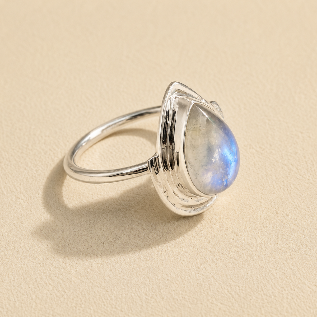 Silver teardrop moonstone ring showing blue glow on teardrop stone and slim band