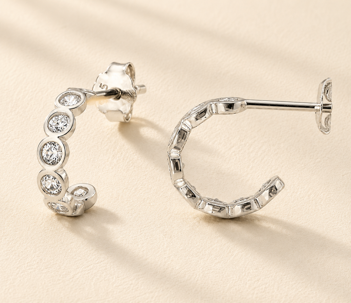 Silver-tone huggie hoop earrings with round clear stones, hinged closure