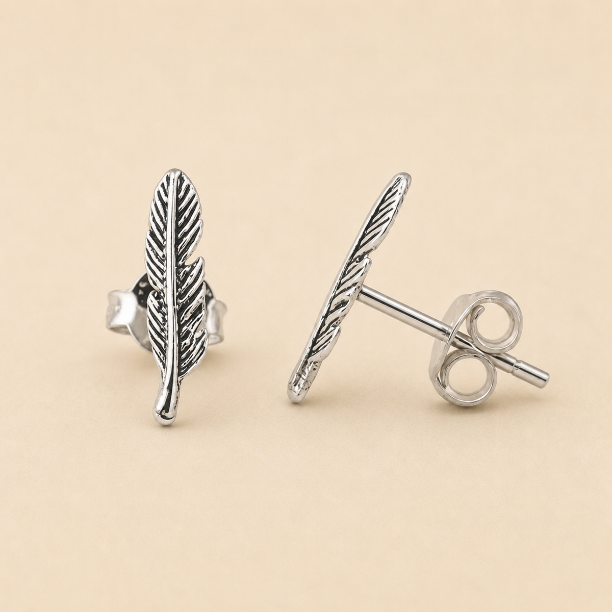 Silver-tone feather stud earrings with vertical leaf pattern, round post back