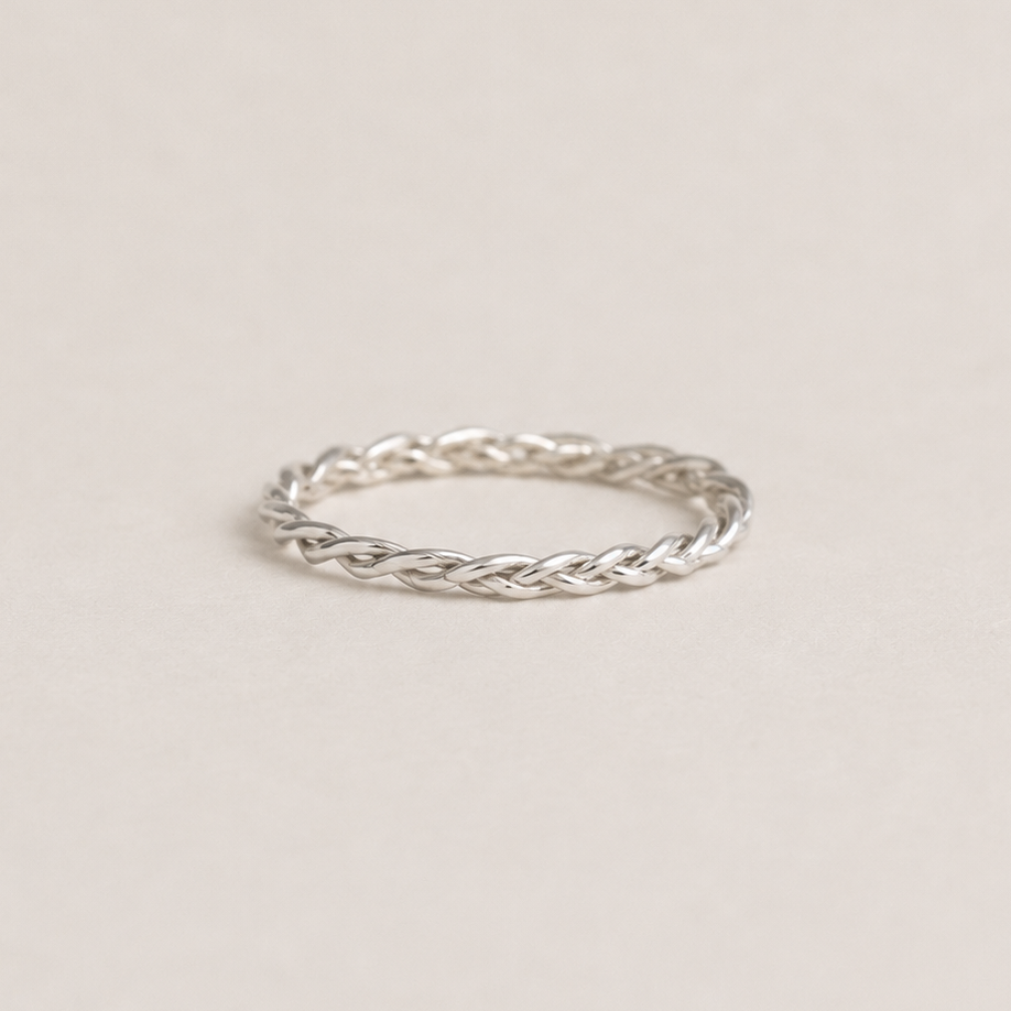 Silver braided ring on a light beige background