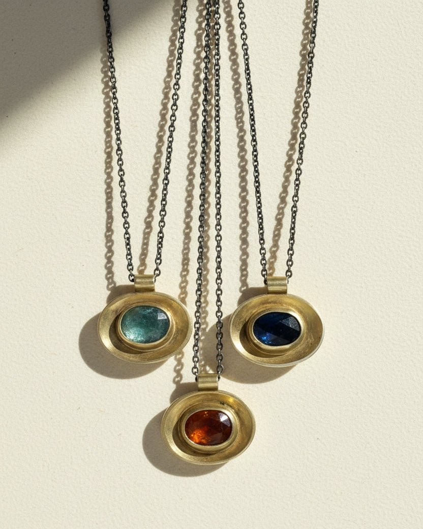 Oval pendant set on silver chains: green, blue, and red stone centers