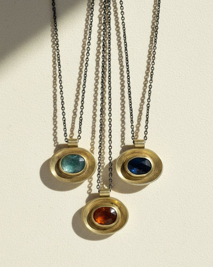 Oval pendant set on silver chains: green, blue, and red stone centers