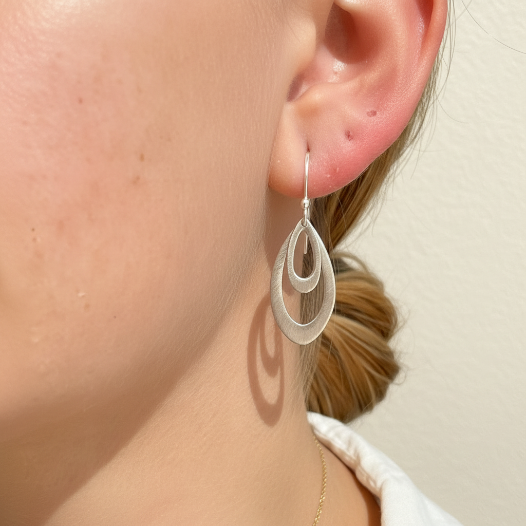 Silver leaf hoop earring with cutout teardrop detail on ear