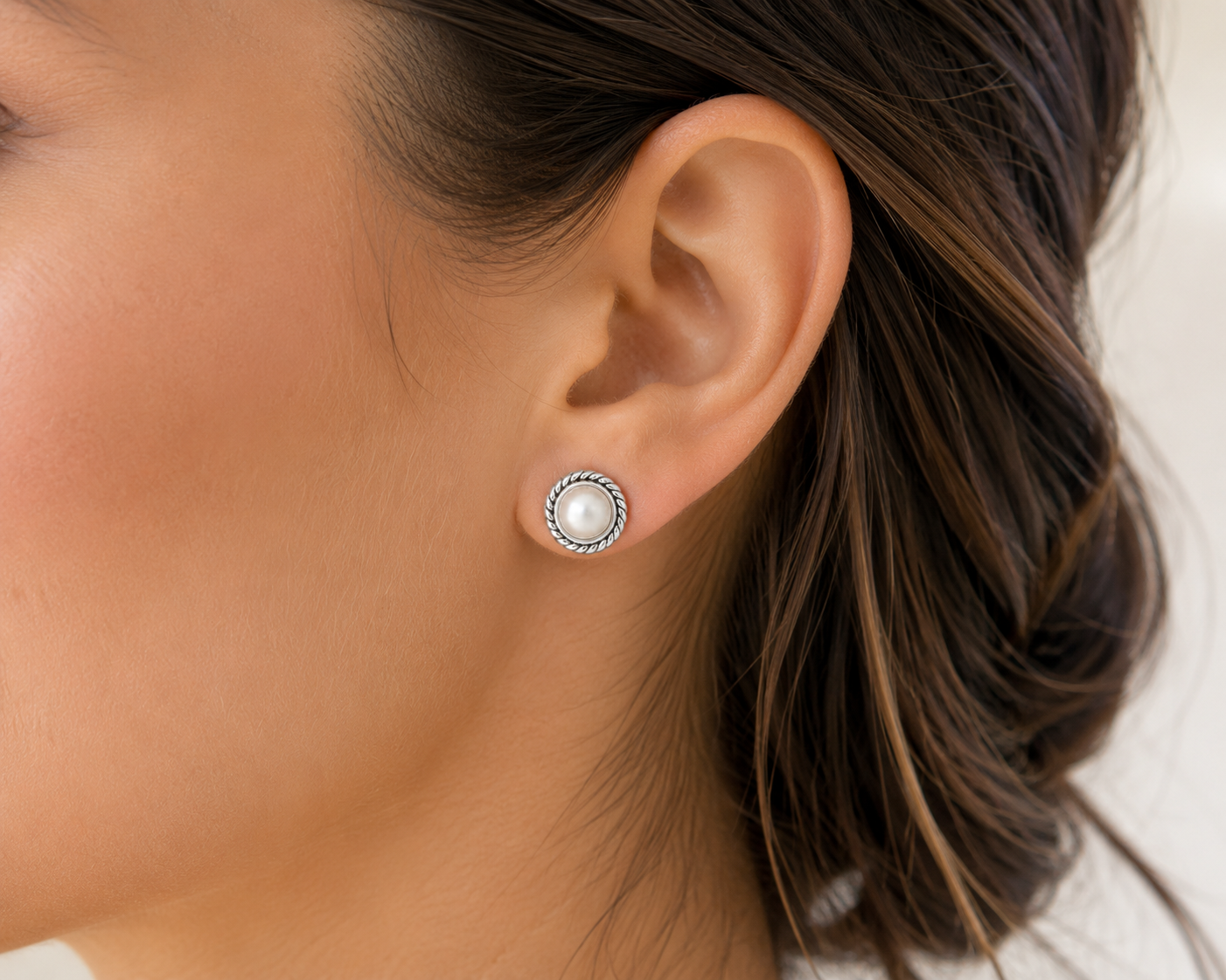 Freshwater pearl stud earring with rope-textured round bezel on ear