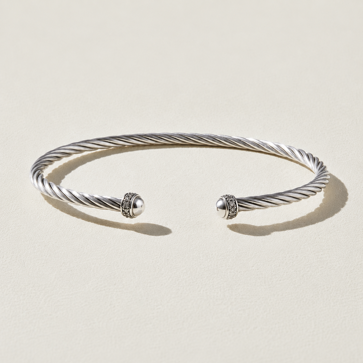 Twisted cuff bracelet with silver-tone wire and two round CZ-studded end caps.