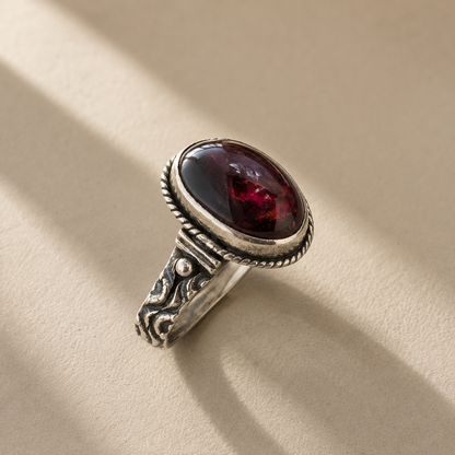 Oval garnet cabochon ring, engraved silver shoulders around deep red stone
