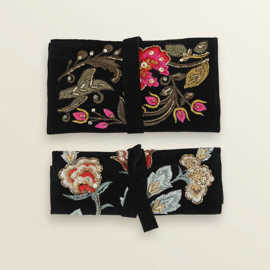 Two black embroidered clutch bags with floral and leaf designs on a white background
