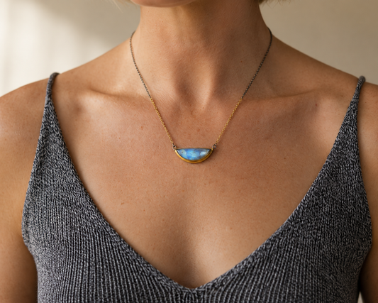 Gold-tone crescent blue gemstone necklace worn on neckline