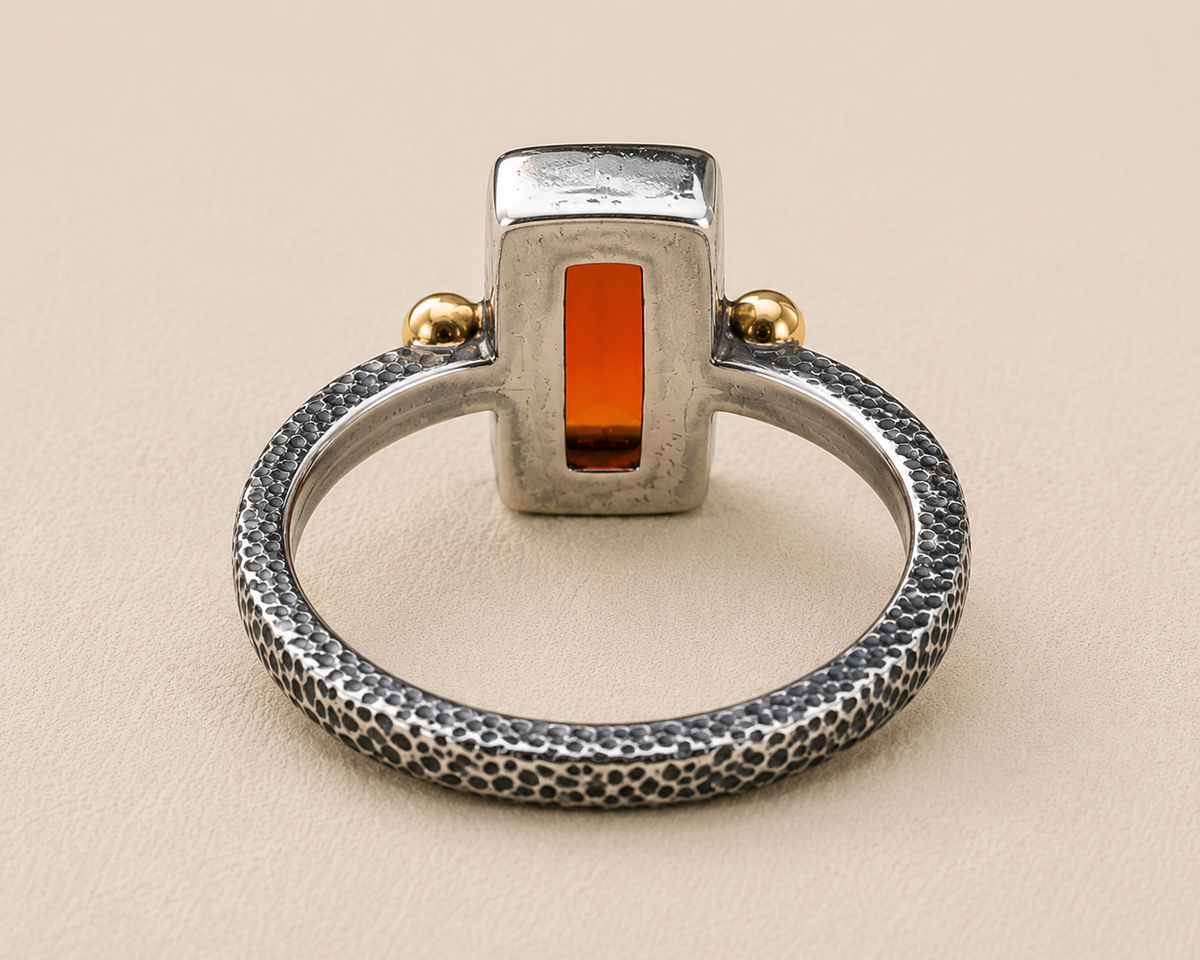 Open-frame carnelian orange stone ring with textured silver band and gold side balls