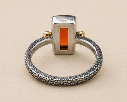 Open-frame carnelian orange stone ring with textured silver band and gold side balls