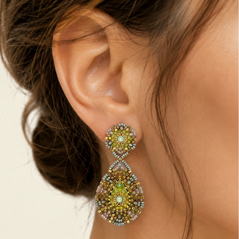Close-up of a woman's ear wearing a decorative earring with green gemstones.