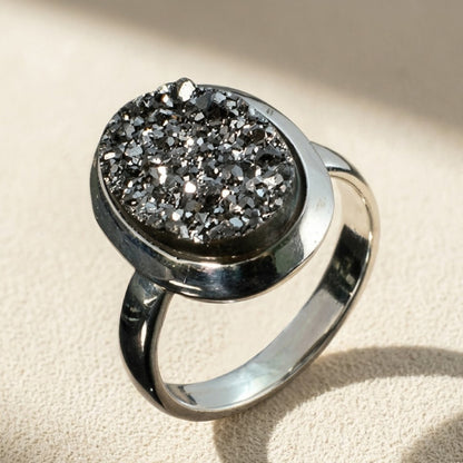 Oval druzy stone ring with dark sparkly center and silver-tone bezel band