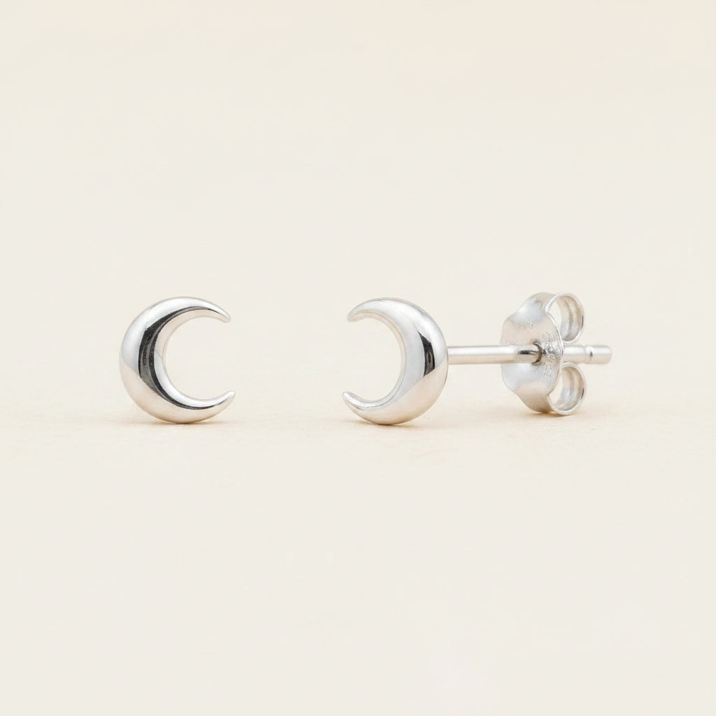 Silver crescent moon stud earrings with circular backing and push-back posts.