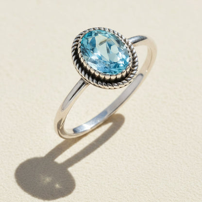 Silver gemstone ring with oval sky-blue stone and braided rope-style bezel