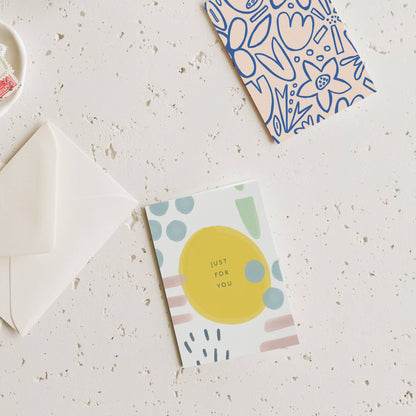 Garden-style mini greeting card with yellow circle and pastel dots, with white envelope.