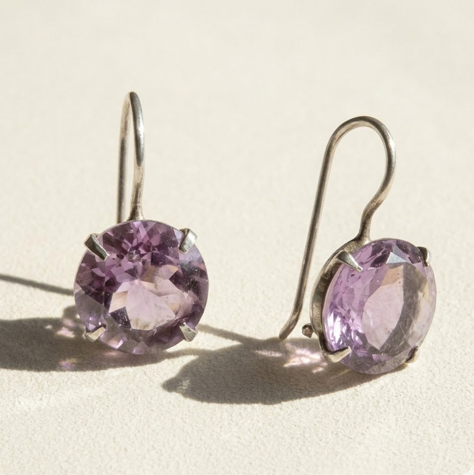 Silver-tone drop earrings with round faceted amethyst-purple stone in prong setting