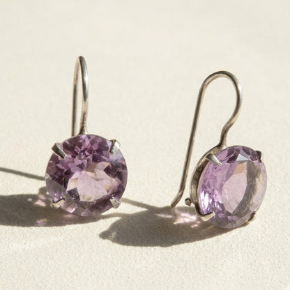 Silver-tone drop earrings with round faceted amethyst-purple stone in prong setting