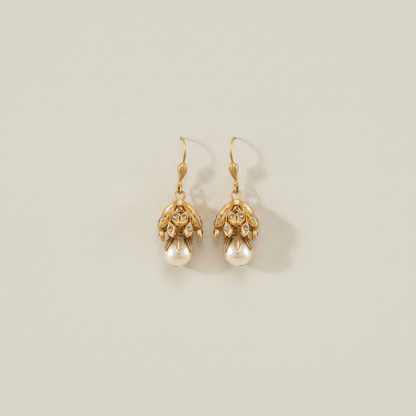 Gold-tone drop earrings with filigree caps and hanging faux pearl, side view