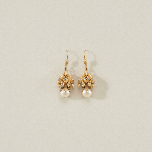Gold-tone drop earrings with filigree caps and hanging faux pearl, side view