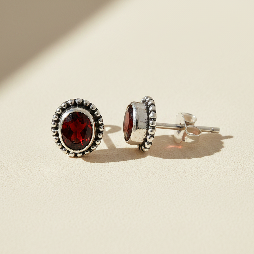 Gemstone stud earrings with red oval center and silver beaded halo
