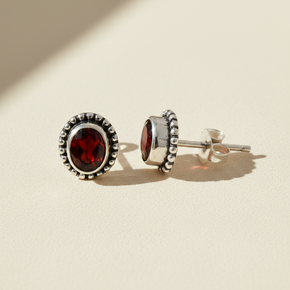 Gemstone stud earrings with red oval center and silver beaded halo