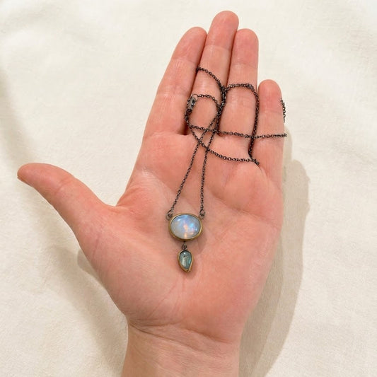 Silver chain drop necklace with blue oval pendant and green teardrop lower charm
