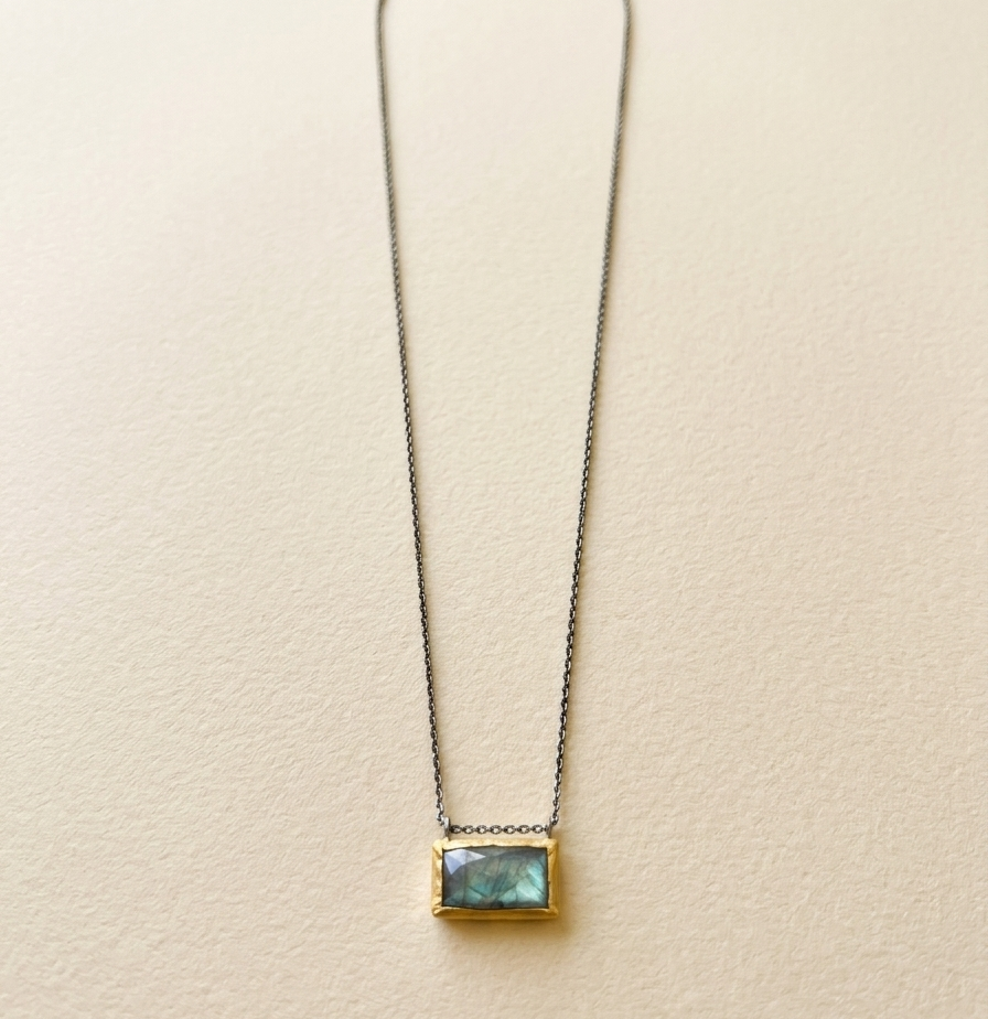 Rectangle pendant necklace with blue-green gem and gold-tone frame on a fine chain