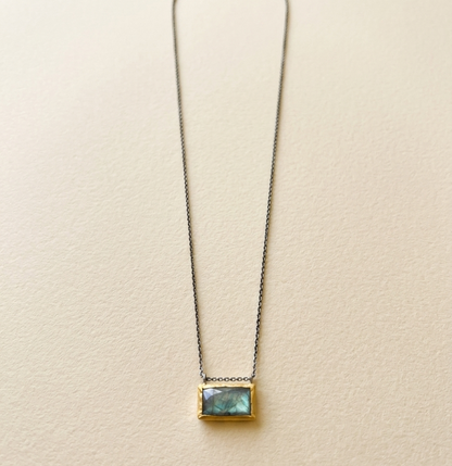 Rectangle pendant necklace with blue-green gem and gold-tone frame on a fine chain