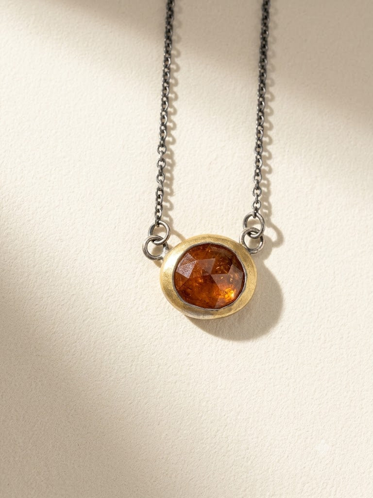 Round amber gemstone pendant necklace with gold-toned rim and linked dark chain