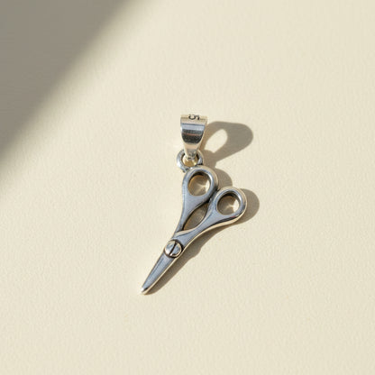 Scissors-style pendant with circular accents and small trim bail