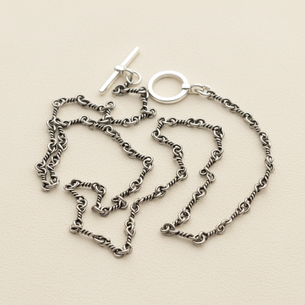 Silver chain necklace on a white stand with a white background