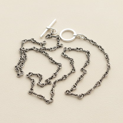 Silver chain necklace on a white stand with a white background