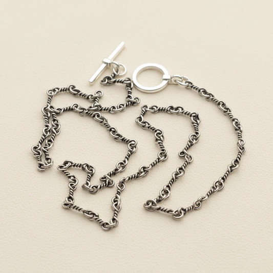 Silver chain necklace on a white stand with a white background