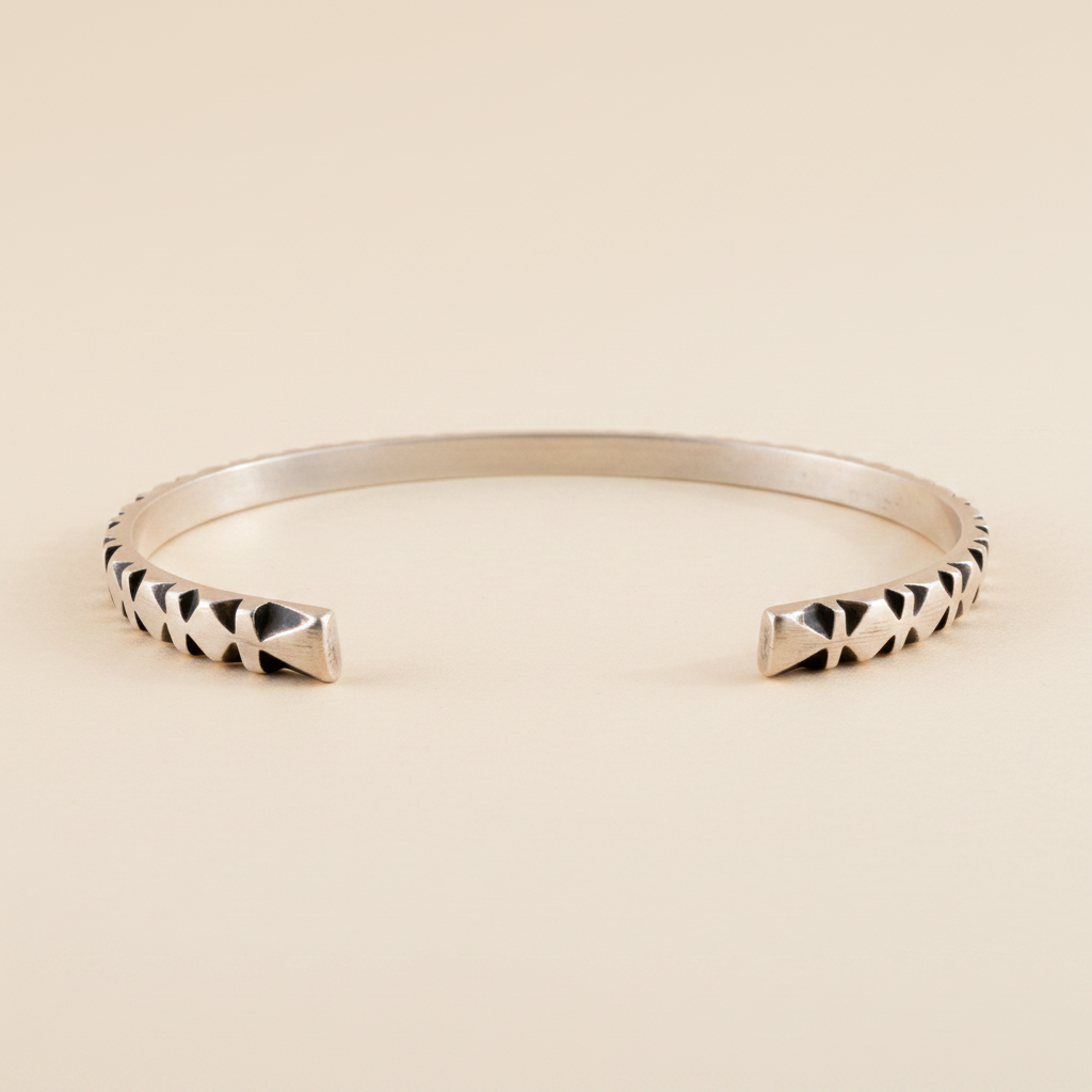 Silver cuff bracelet with black-and-white carved diamond stripe detail at ends