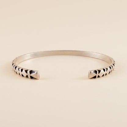 Silver cuff bracelet with black-and-white carved diamond stripe detail at ends