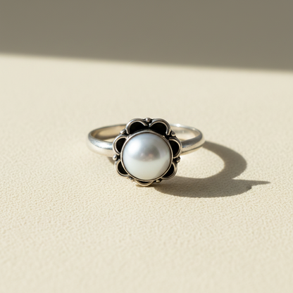 Round white pearl ring with dark decorative border around the bezel
