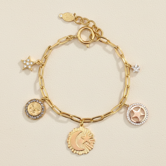 Gold-tone charm bracelet with circular and star charms, crystal accents, clasp links