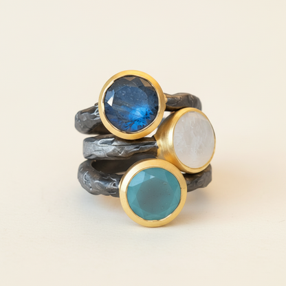 Stacked hammered band chalcedony rings with blue, white, and teal stones, gold bezels