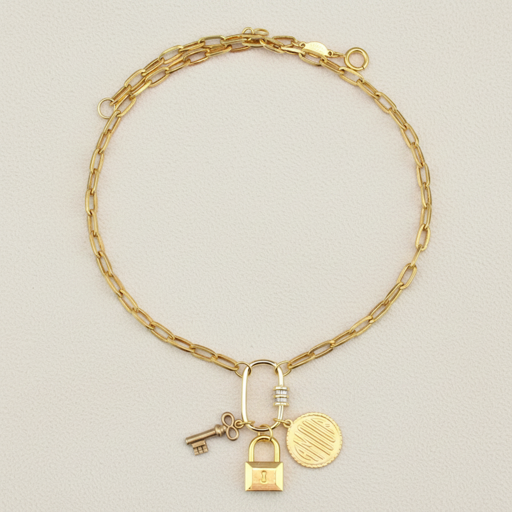 Gold-tone charm necklace with lock, key, and round coin pendant on curb chain