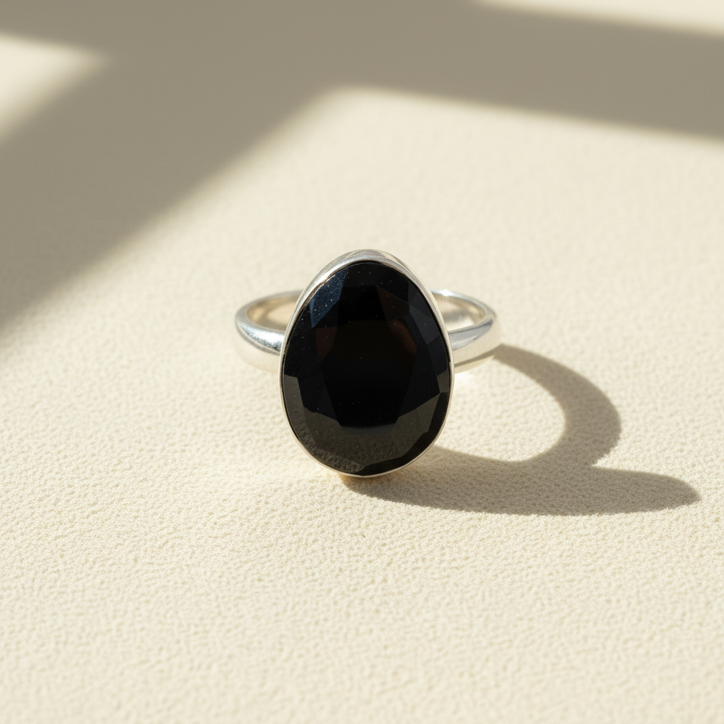 Oval black faceted gemstone silver band ring, front view