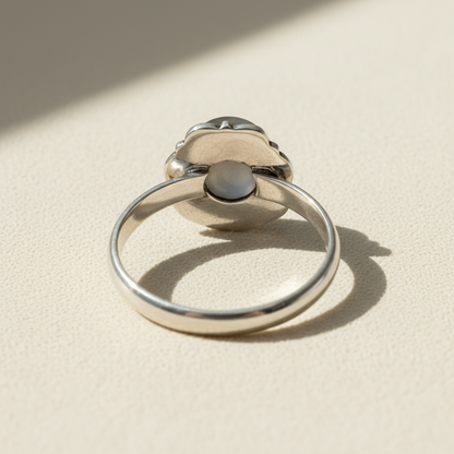 Silver-toned pearl ring with round white pearl and dark central setting