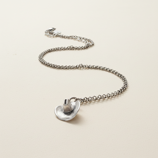 Silver-tone cowboy hat pendant necklace laid out with link chain and hat charm