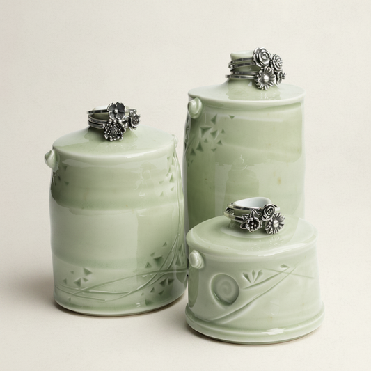 Set of three green ceramic jars with decorative lids on a white background