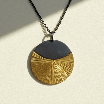 Mixed metal circular pendant necklace with black top and gold textured fan half