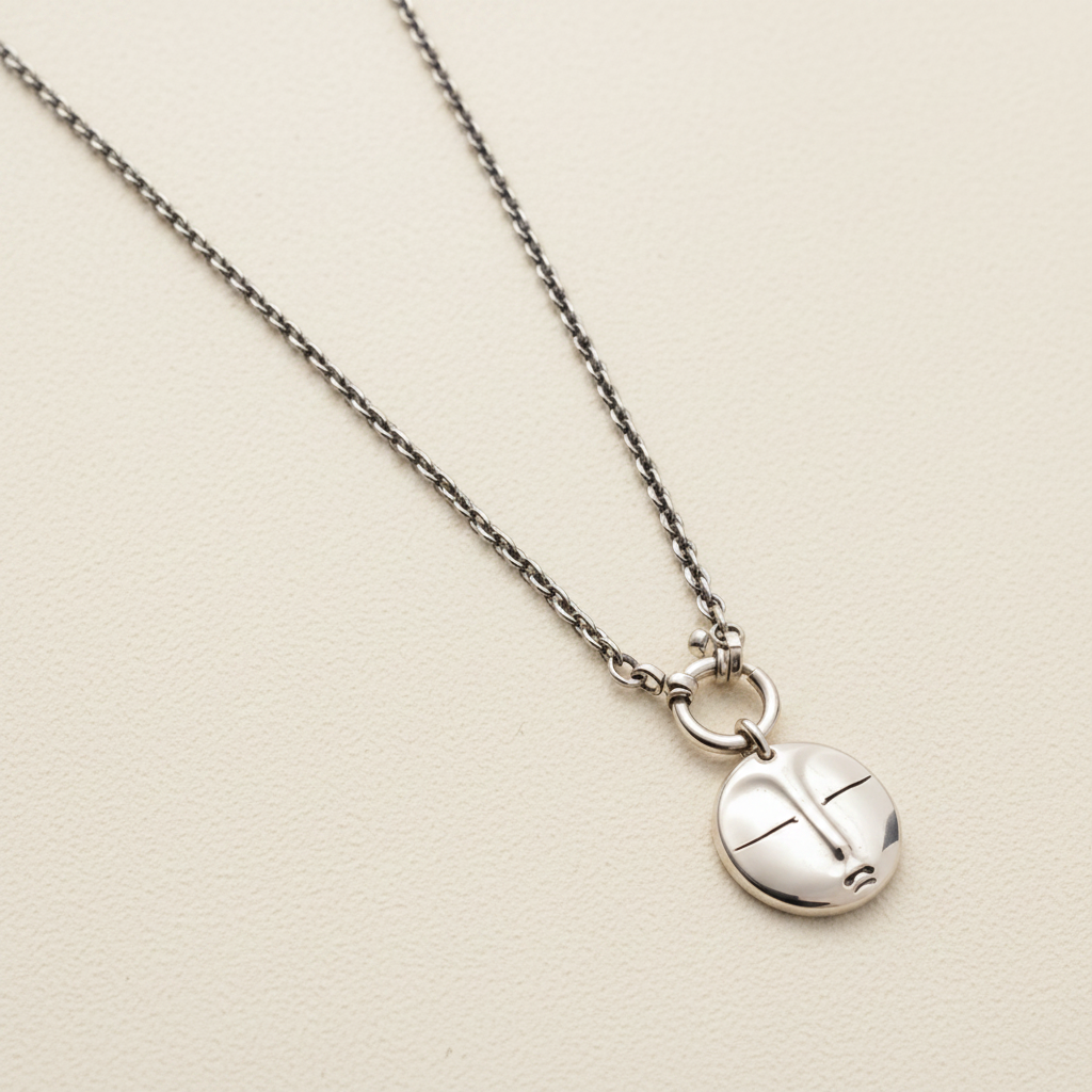 Silver necklace with a round pendant on a white background