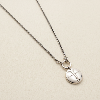 Silver necklace with a round pendant on a white background