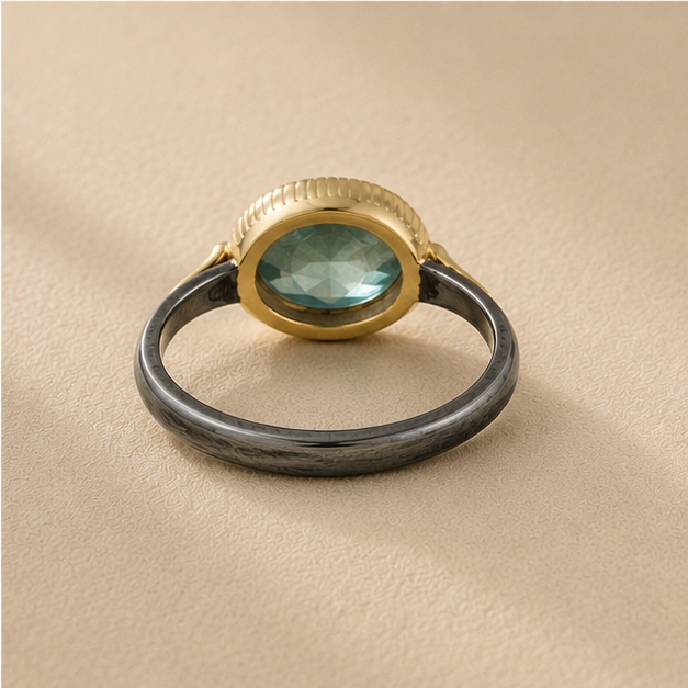 Two-tone apatite ring front view: oval blue-green stone, gold top bezel, dark silver band