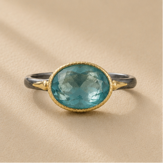 Two-tone apatite ring with oval blue-green stone and gold bezel on dark silver band