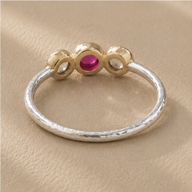 Silver ring with gold crown, pink center ruby, and two side cool-toned round stones