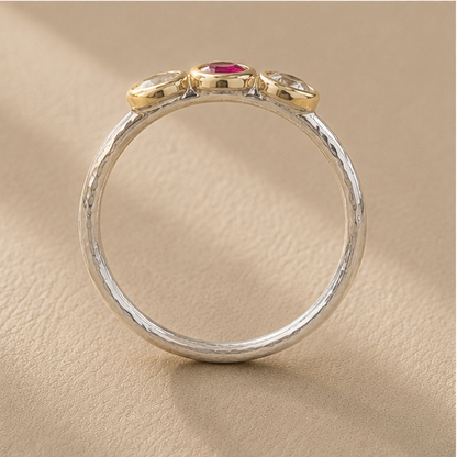 Silver circular band with raised edge detail and small pink stone under top bezel